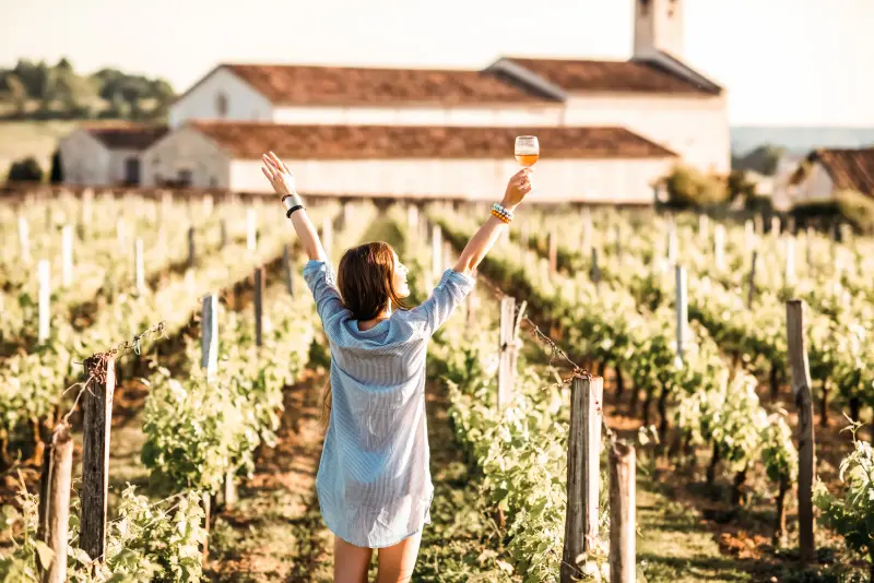 Elegant woman enjoying wine in a vineyard during autumn luxury travel with a Top Companions escor